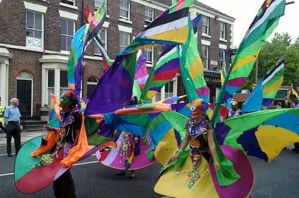 Dancers in colourful carnival costumes performing in a Georgian Liverpool street