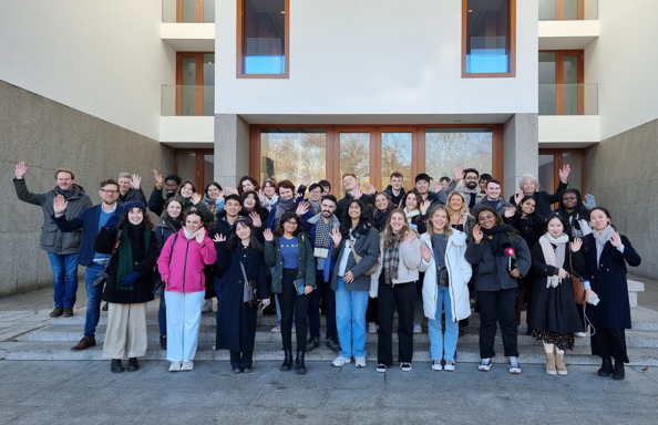 Group of students of mixed ethnicities standing in front of a modernist building on a cold day
