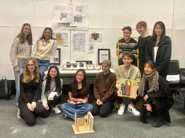 Eleven students standing in front of a display of their project holding models