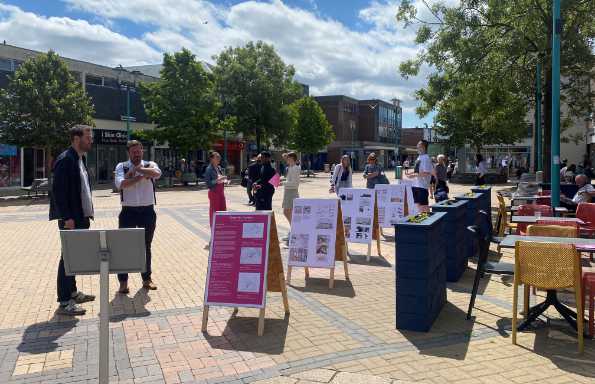 Display board in a busy street covered in post it notes.