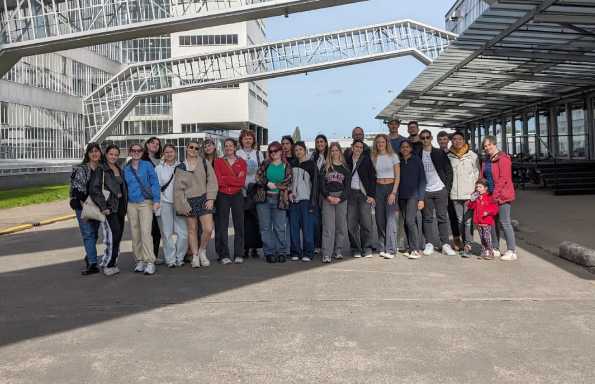 A group of students and staff standing in the middle of a road surround by steel and glass buildings.