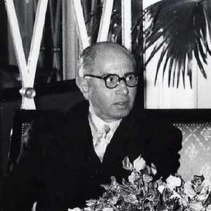 Mahmoud Riad sitting at a table with floral arrangement in front