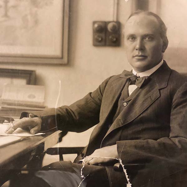 Sepia toned photograph of Charles Reilly sitting at a desk