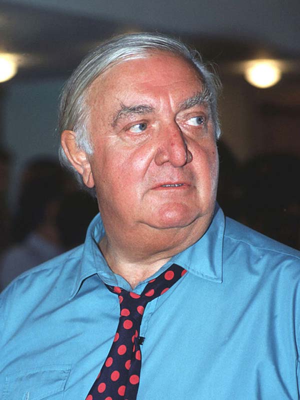 Photograph of Architect James Stirling wearing a blue shirt and red and black spotted tie