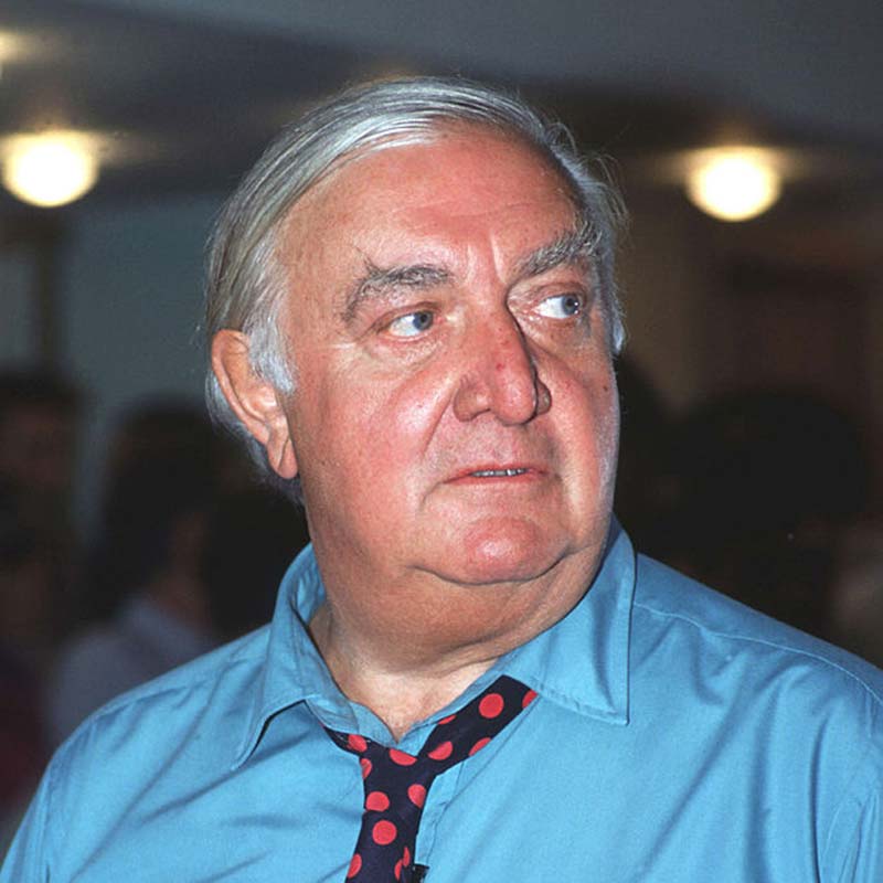 Photograph of Architect James Stirling wearing a blue shirt and red and black spotted tie