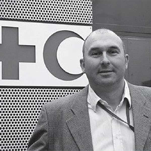 Man standing in front of front of building with Red Cross and Red Crescent symbols on wall