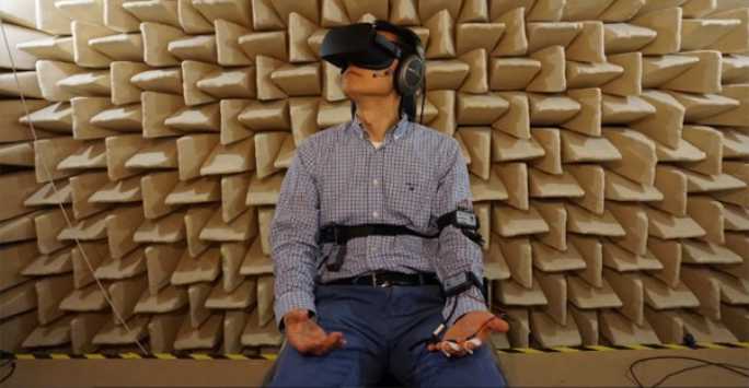 A man wearing a virtual reality headset sitting in an anechoic chamber.