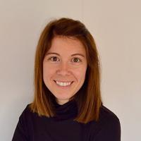 Smiling woman with shoulder length brown hair wearing a polo neck sweater.