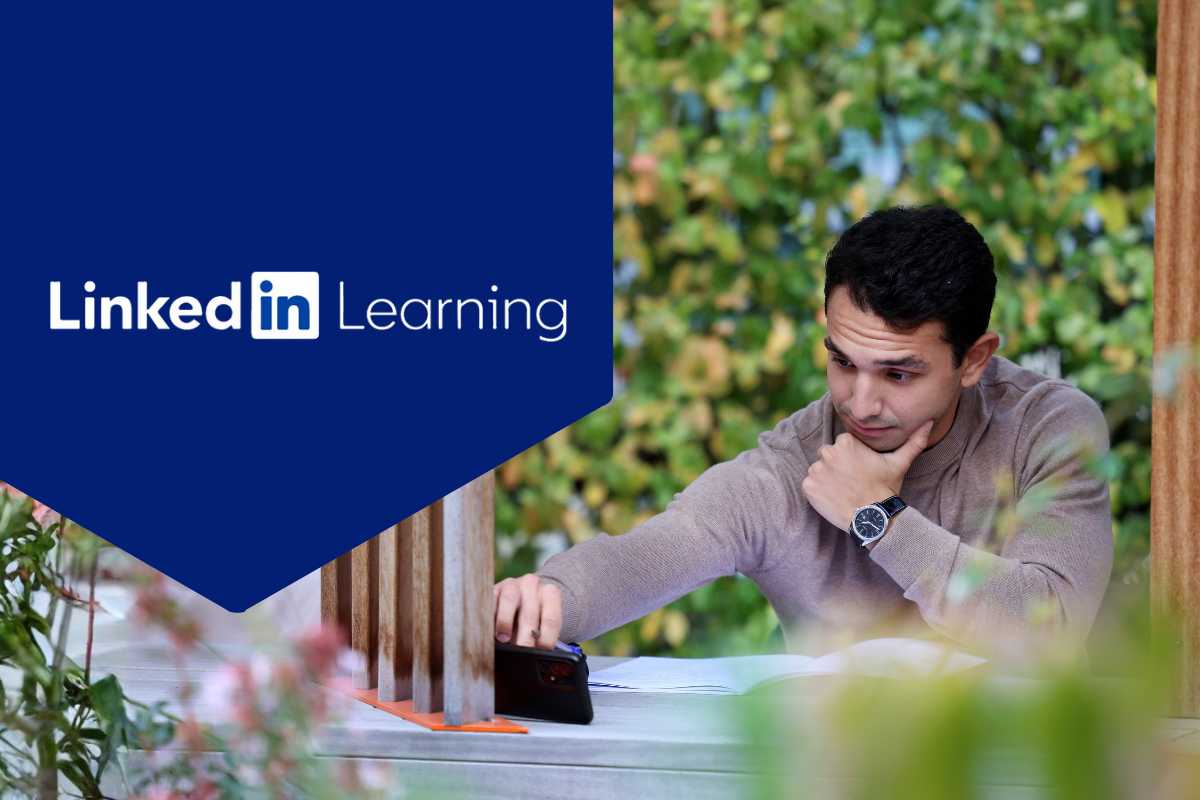 A student on campus in Career studio on computer, LinkedIn logo