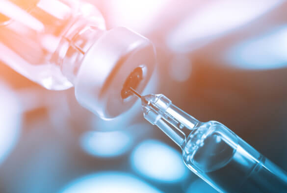 A syringe is being filled from a vial.