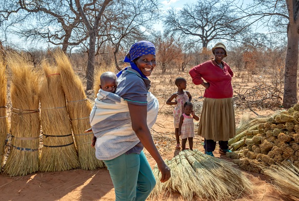 Two women with their children are walking through an African landscape
