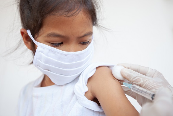 A child is being prepared for an injection in their arm