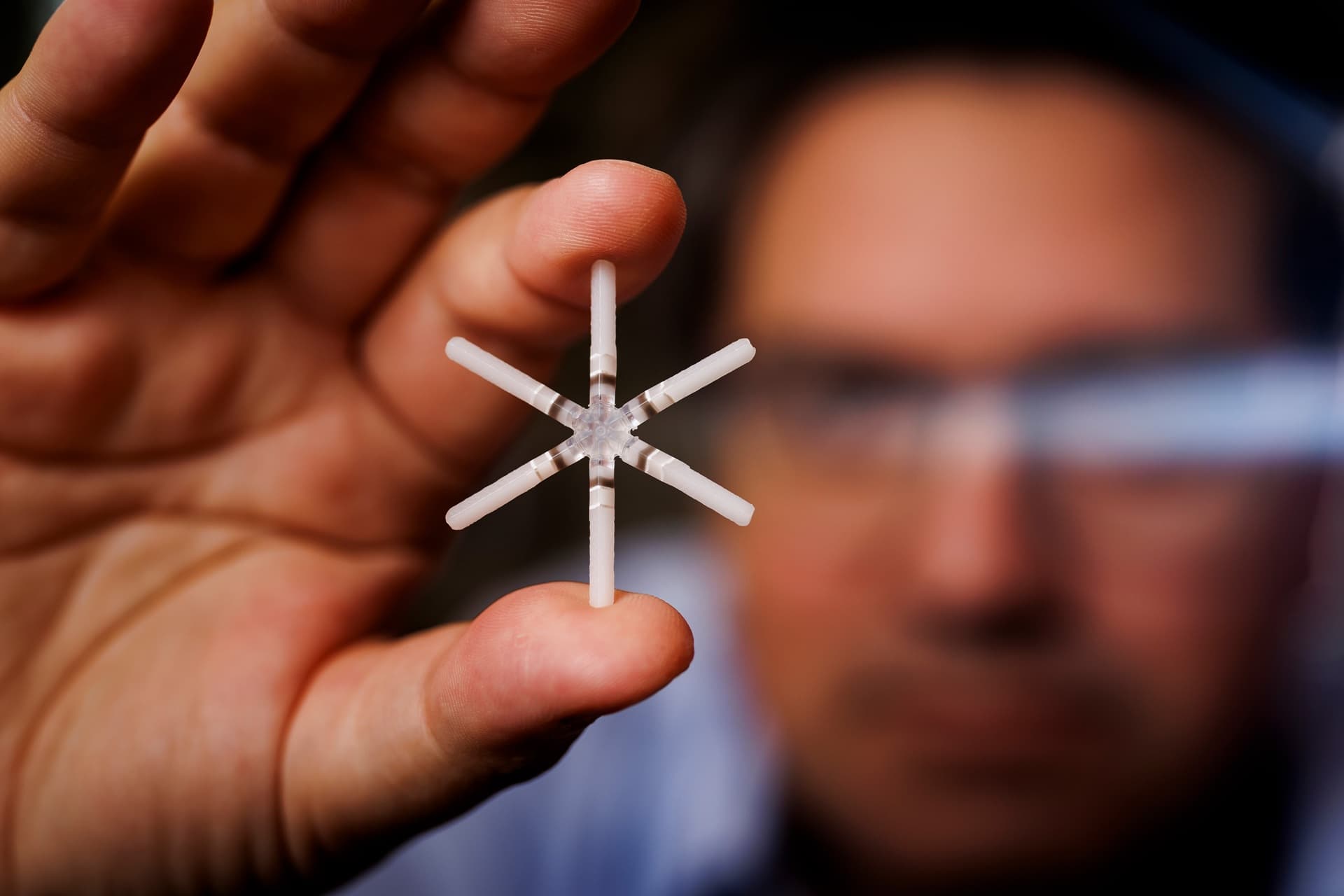 A pronged instrument is being held up to the camera between thumb and forefinger.