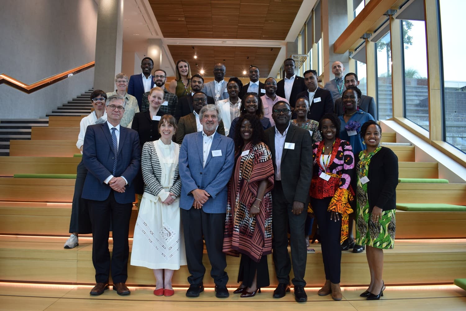 Members of the community of practice are standing in a spacious, light, raised area in The Spine in Liverpool, UK. Everyone has a friendly smile for the camera.