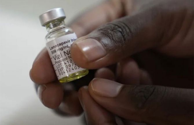 a hand is holding a vial of medicine labelled lenacapavir