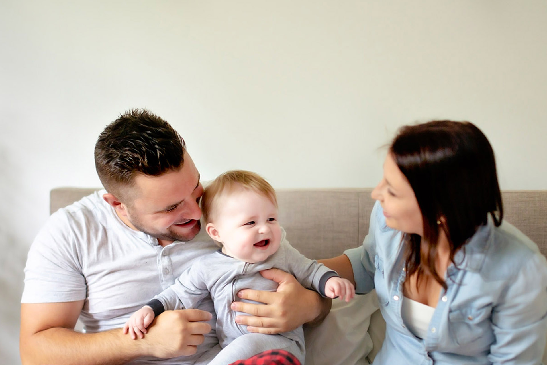 Mother and Father sitting on a couch with their baby