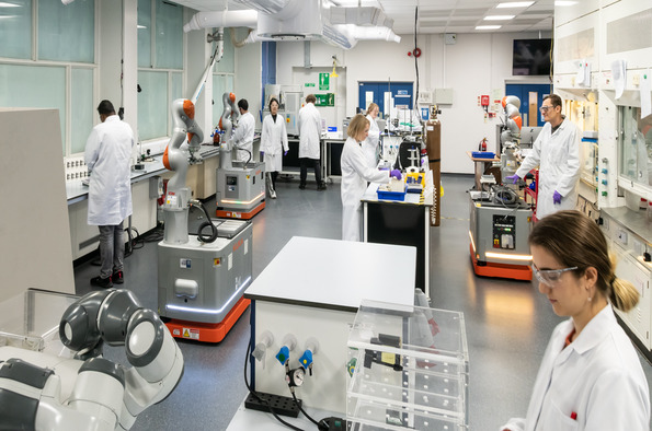 A diverse group of scientists collaborating in a laboratory, engaged in research and experiments at workstations.