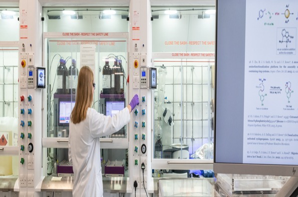 A woman in a lab coat is focused on her work while using a computer in a laboratory setting.
