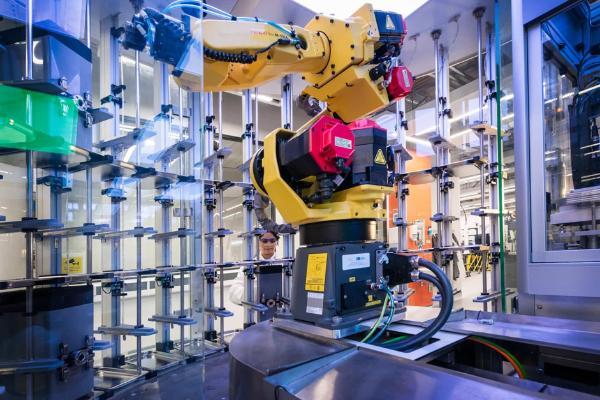 A robotic arm operates on a machine in a factory setting, showcasing advanced automation technology in action.