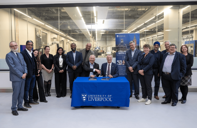 A group of people in a factory around a table, where an MoU has just been signed