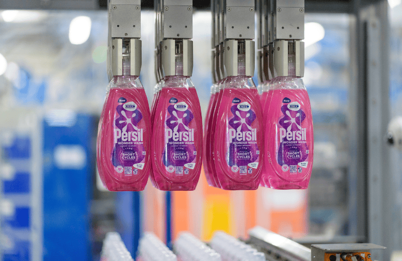 Bottles filled with pink laundry detergent being filled in a lab