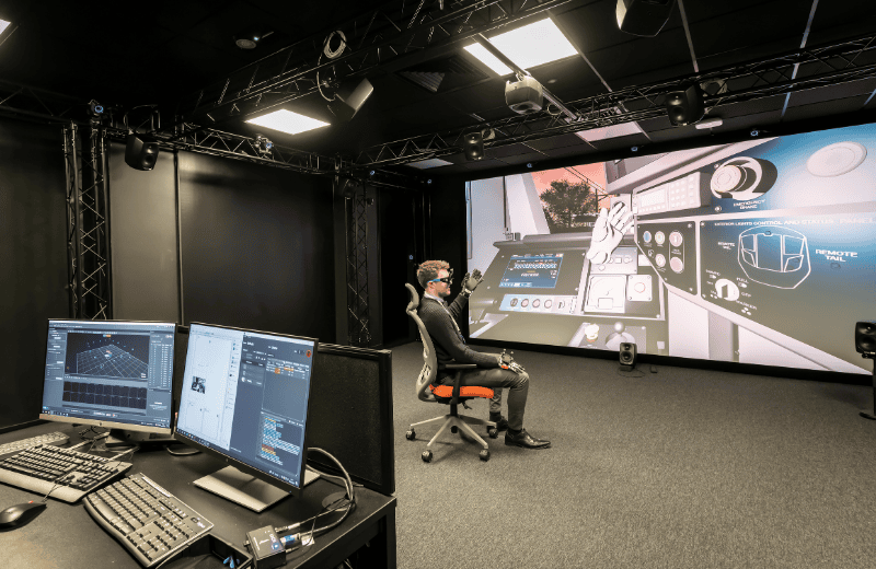 Engineer in digital transformation lab, wearing VR goggles in from of a large screen