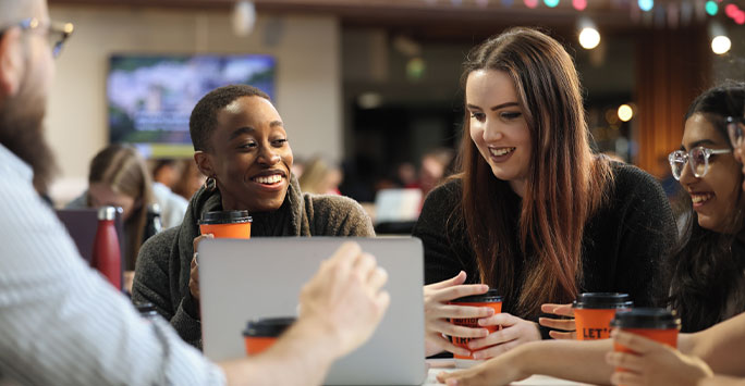 Students sitting around laptop drinking coffee