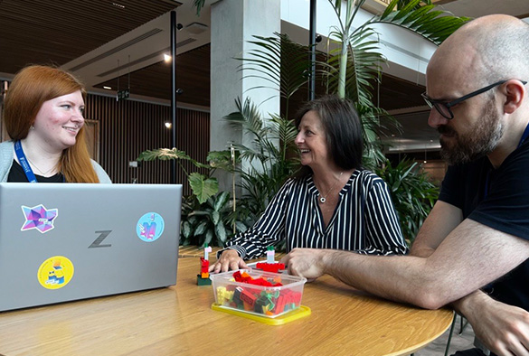 Process improvement team discussing workshops while sitting at a table with lego and a laptop