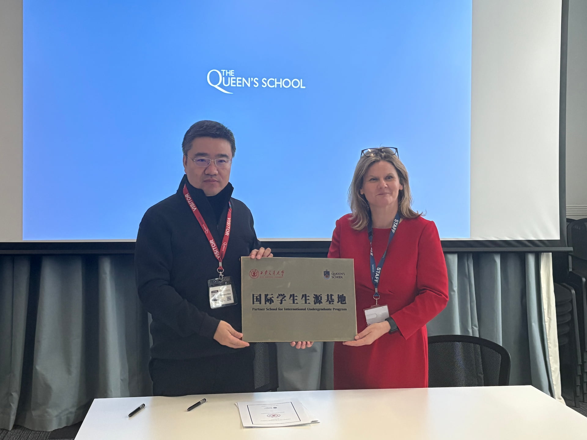 Professor Wen Guangrui stood with The Queen's School leadership representative, holding a plaque, having just signed the Partner School cooperation agreement