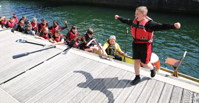 Dragon boat at a jetty while boy walks away cheering