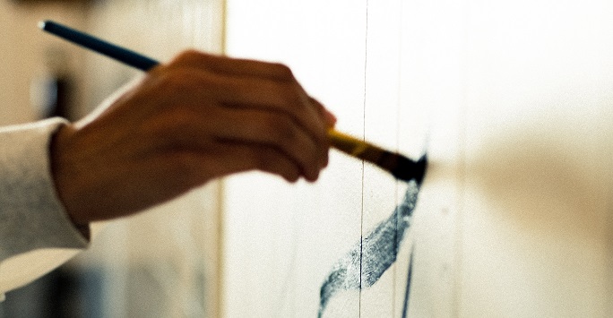 A hand doing Chinese painting with a brush and ink