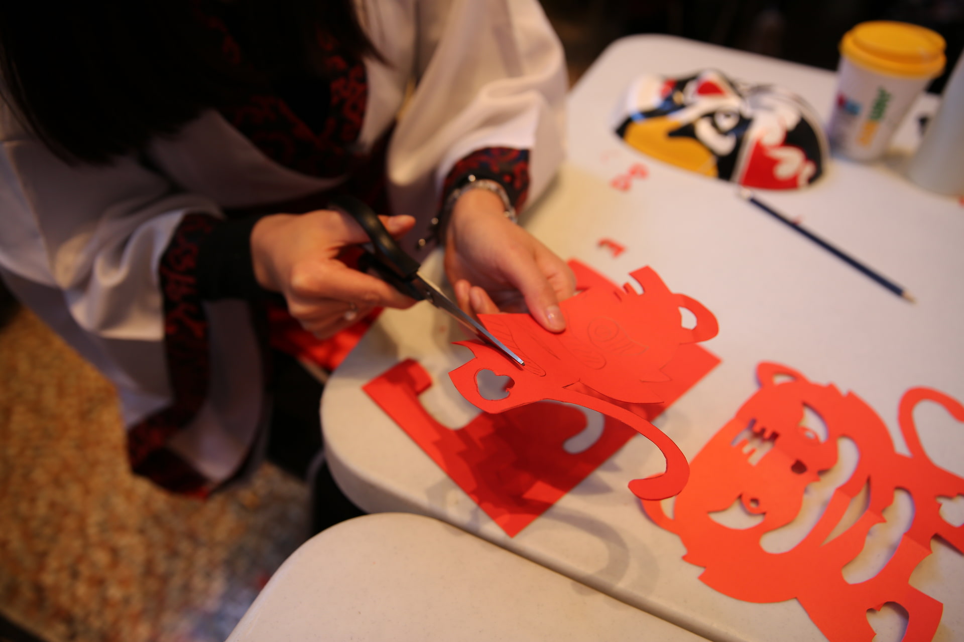 A person cutting out a shape from red paper.