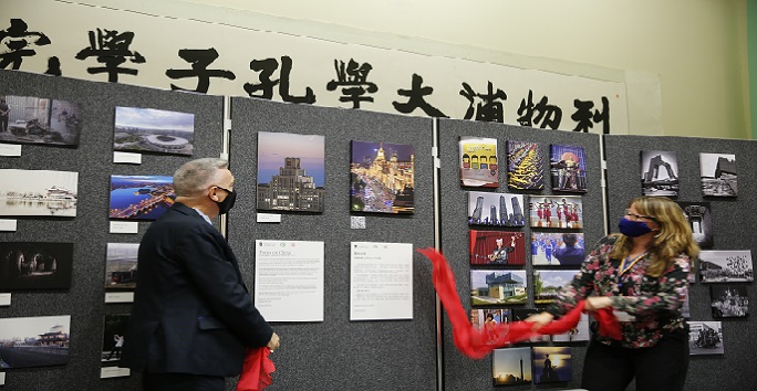 Man and woman removing red silk banners to open photography exhibition