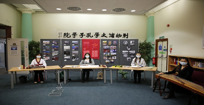Four Chinese teachers seated in front of a photography exhibition