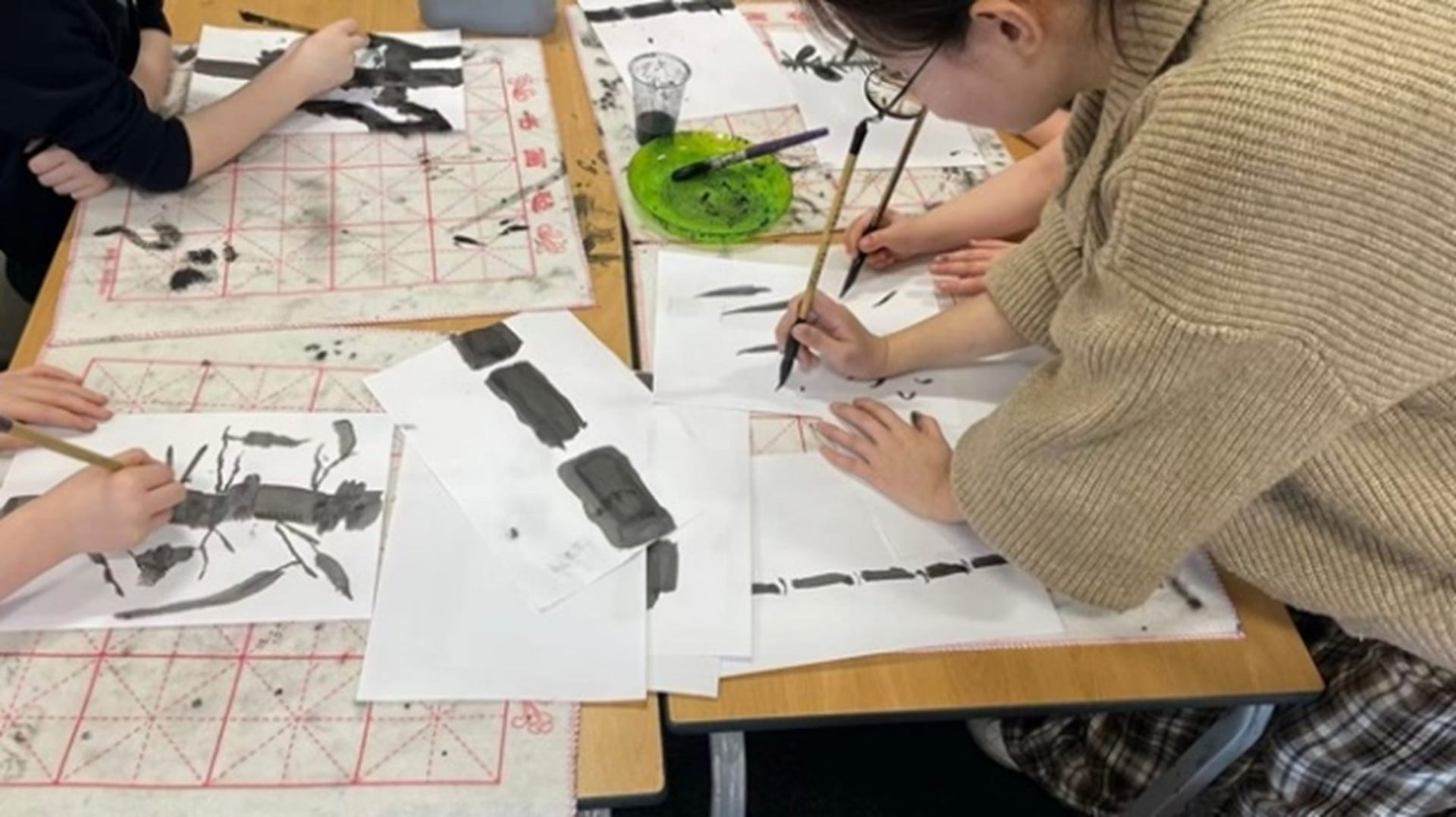 People writing Chinese characters in ink.