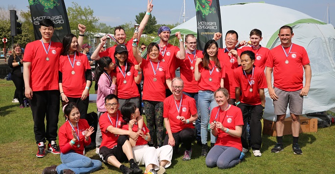 A group of people celebrating with bronze medals and a trophy