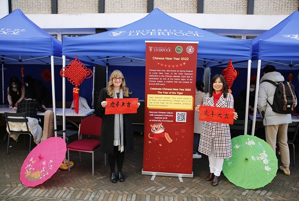 Two women holding Chinese Calligraphy signs at a Chinese New Year stall