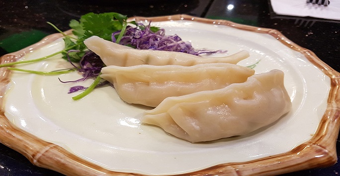 Three dumplings on a plate with salad