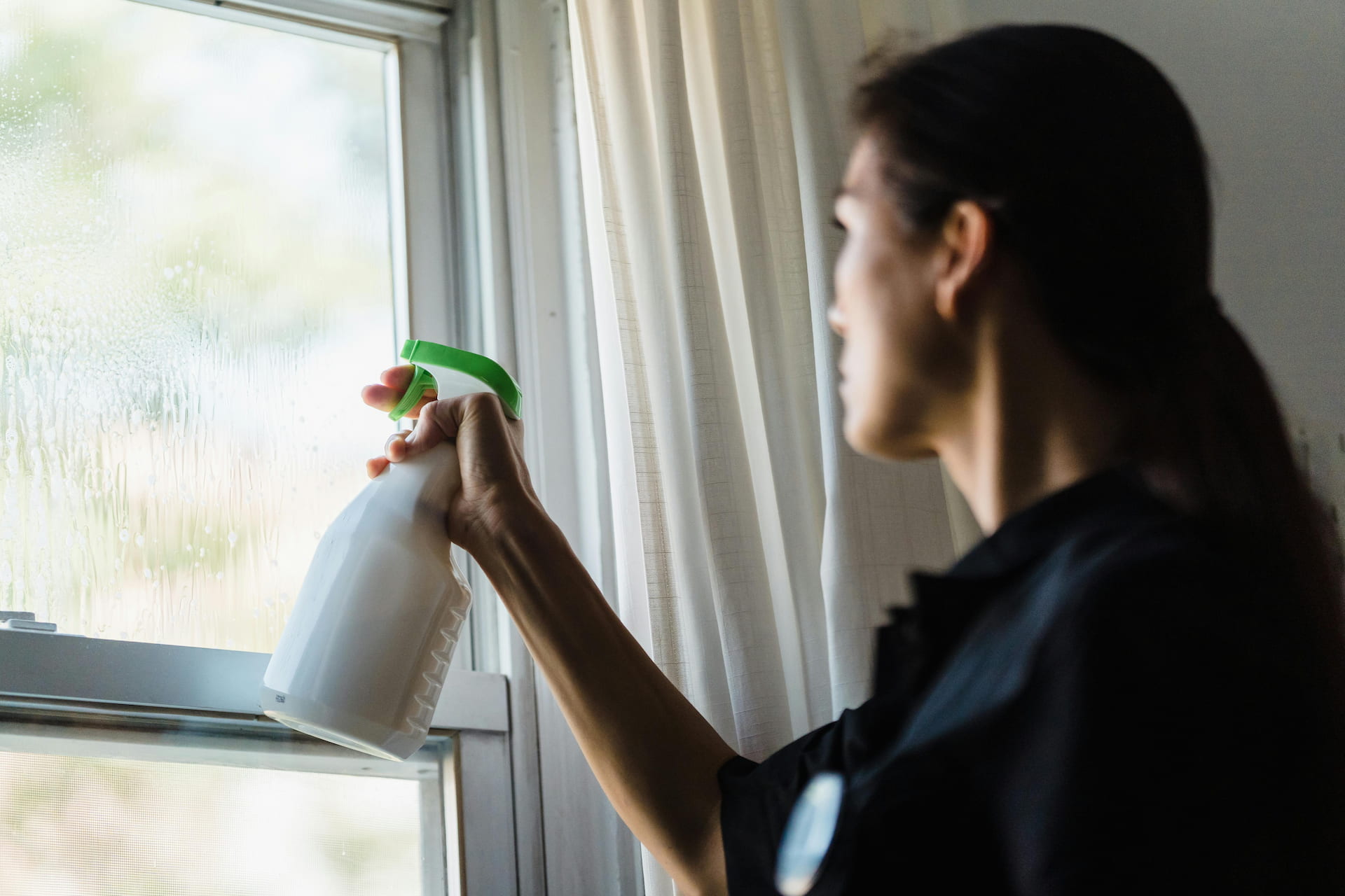 Woman cleaning a window with a spray bottle.