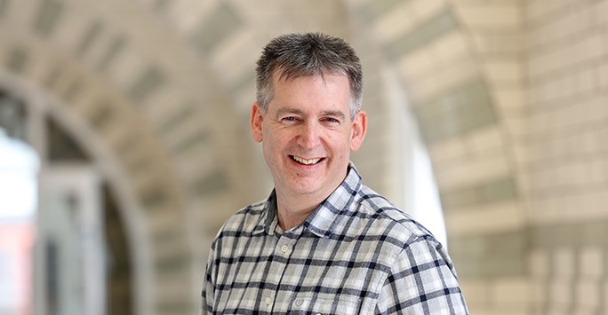 A smiling man wearing a checked shirt