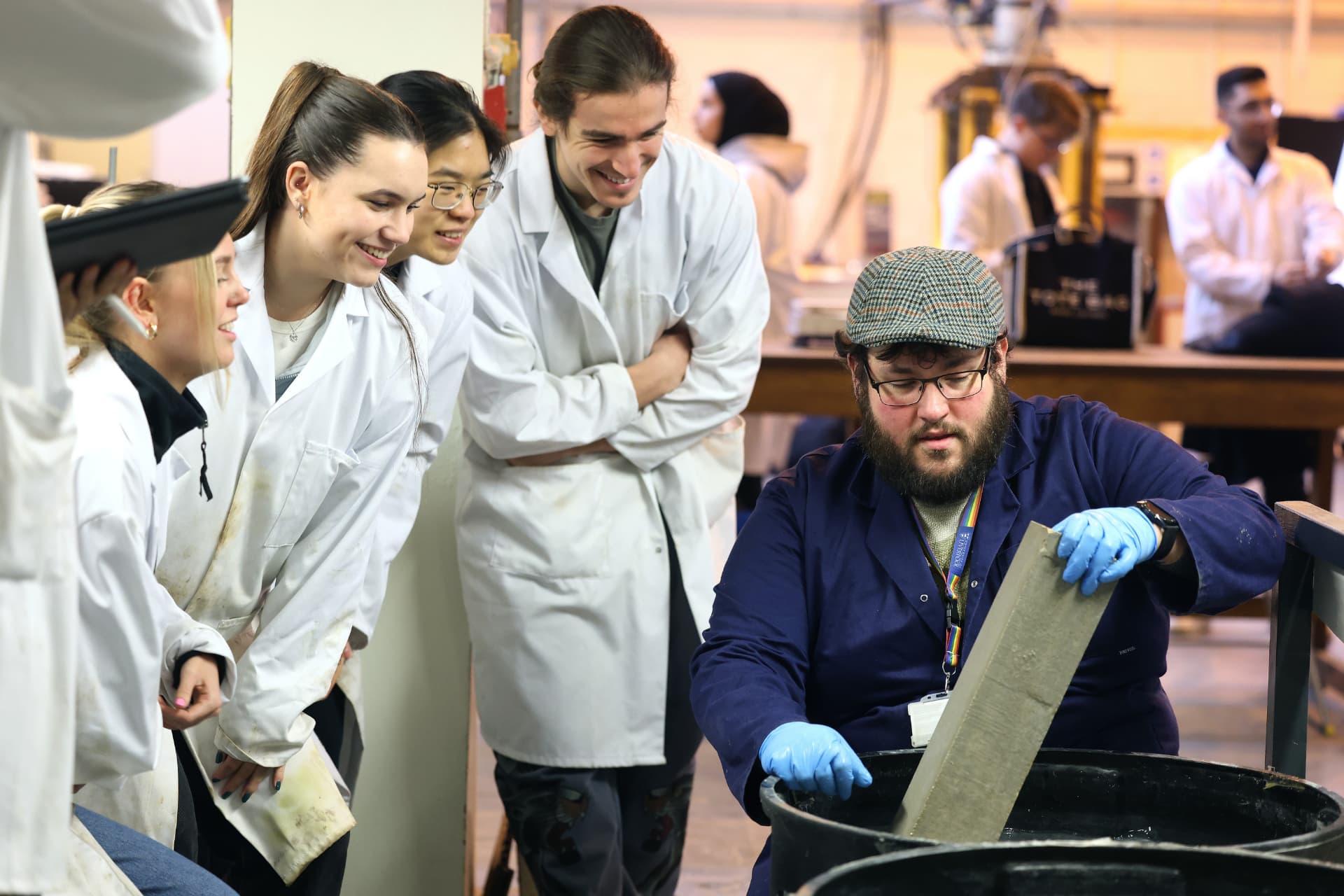 A group of civil engineering students wearing white lab coats watching a demonstration.