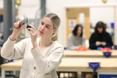 A woman measuring an object in a mechanical engineering lab.