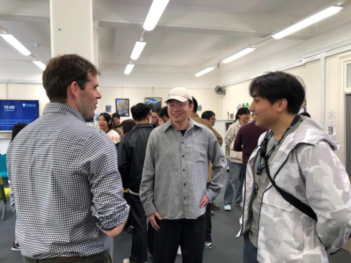 Two PSE students and a teacher talk during a social event at the Language Lounge
