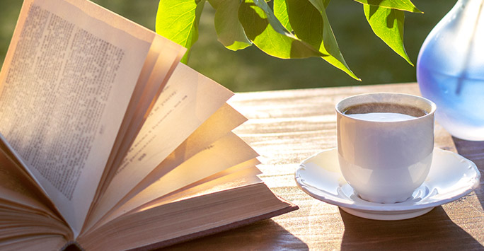 Book, coffee and vase on a table in a garden