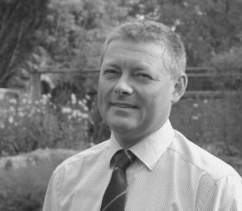 Greyscale portrait of white male with short brown hair wearing a shirt and tie