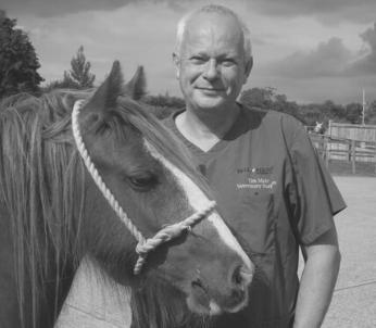 Greyscale image of white male in scrubs standing next to horse