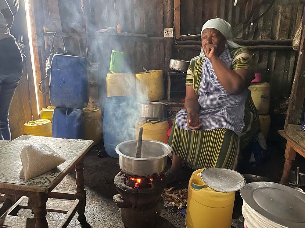Cameroonian woman in home burning fuel for cooking in pot