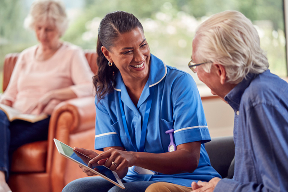 Nurse speaking to an elderly patient in a care facility.