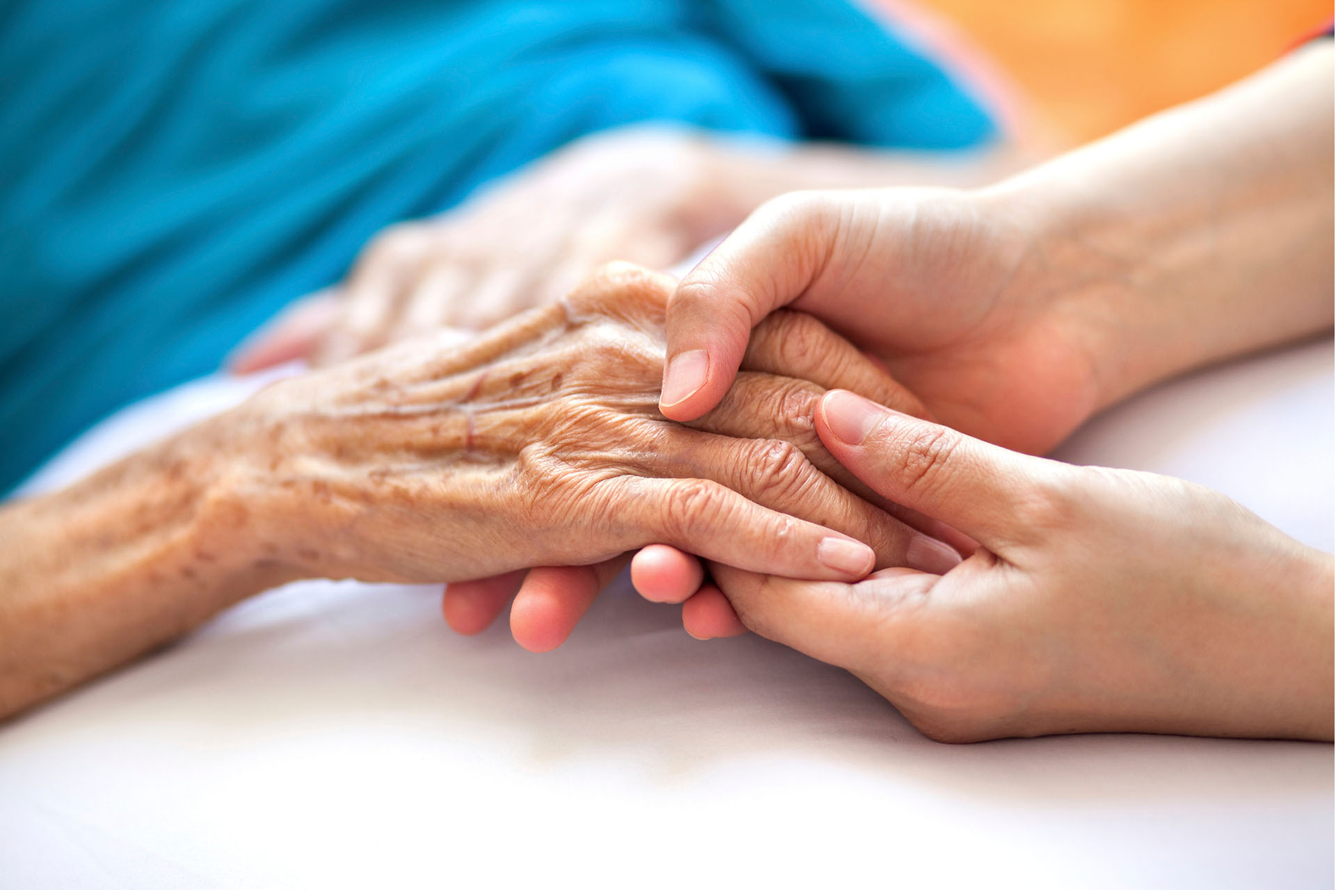 image of doctor or nurse holding the hands of an elderly woman
