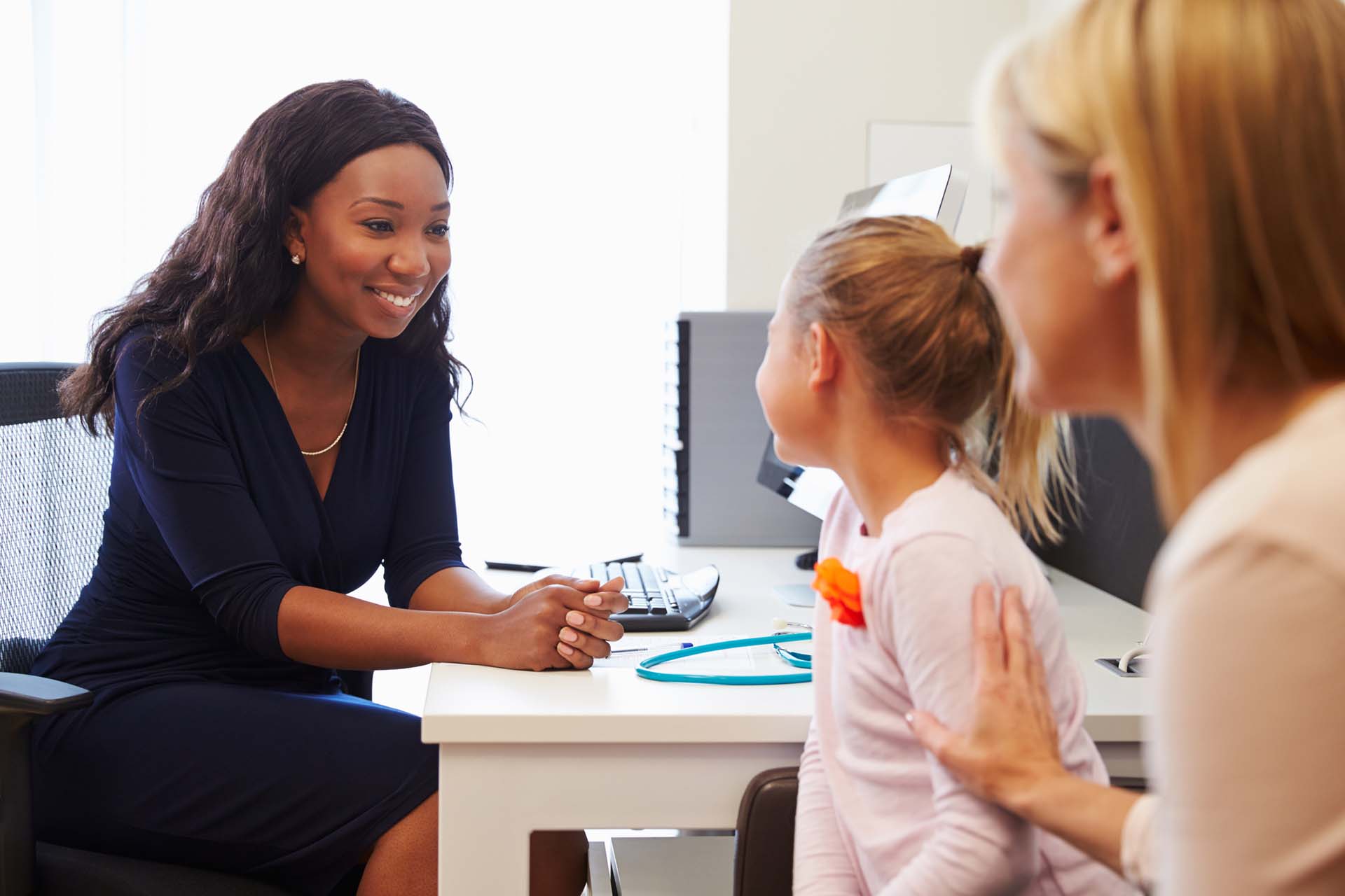 image of child with parent in doctors office speaking to smiling doctor